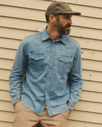 fit model leaning against the wall wearing The Glacier Shirt in Washed Indigo Denim
