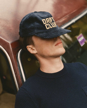 fit model sitting on a car wearing The Mercer Cap in Drift Club