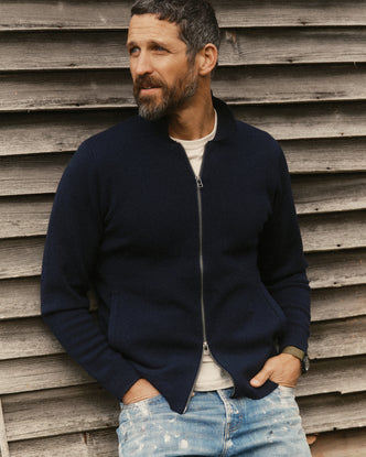fit model leaning against the wall wearing The Portola Sweater Jacket in Midnight Merino