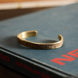 The Hammered Cuff in Brass on a book