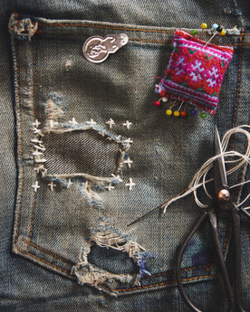 A pair of old jeans patched using the sashiko mending method, Accessories by Taylor Stitch