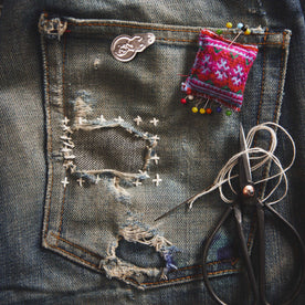 A pair of old jeans patched using the sashiko mending method