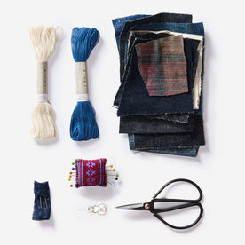 The thread, recycled denim patches, ashiko needles, pins and cushion and needle threader in the Sashiko Denim Repair Kit