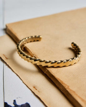 editorial image of The Twisted Cuff in Brass on a piece of paper, Accessories by Taylor Stitch