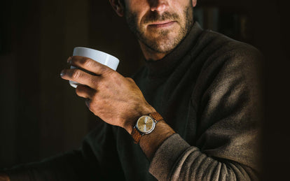 Model drinking a cup of coffee while wearing the 1964 Timex Electric