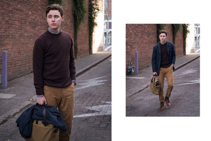 John carrying a messenger bag, walking down a cobbled street.