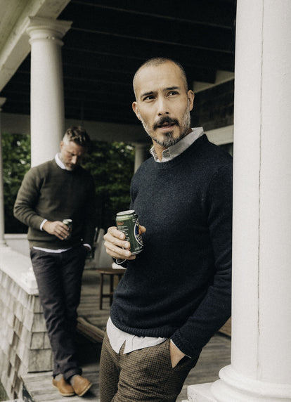 Model wearing The Lodge Sweater in Black Pine while holding a beer