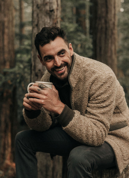 Model sitting with a cup of coffee in The Carson Jacket in Light Khaki Fleece