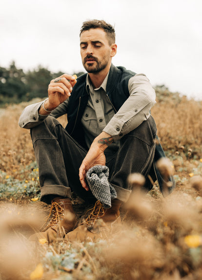 Model sitting in a field in The Saddler Shirt and Workhorse Vest