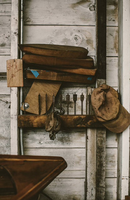 Wood working tools on a rack alongside a well worn cap.