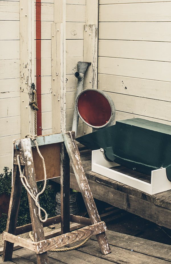 Various marine-related items, leaned up against the side of a white-washed wooden building.