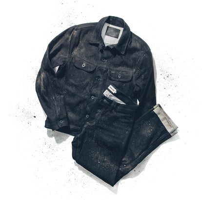 Flat lay of a dyneema denim jacket and jeans on a white background, dusted with dirt.