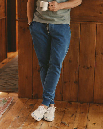 fit model leaning against the wall wearing The Sunset Pant in Washed Indigo Terry