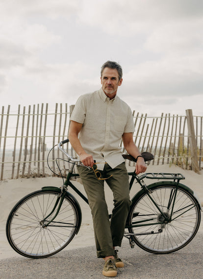 Model wearing The Short Sleeve Jack in Heather Oat, leaning on his bike
