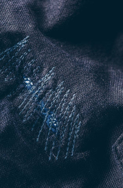 A closeup image of repair work on a dark navy colored garment.
