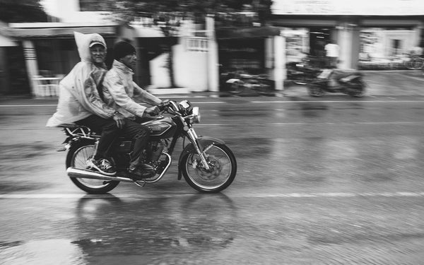 Two guys on a motorcycle, in the rain.