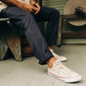 fit model sitting on a bench in The Democratic Foundation Pant in Organic Dark Navy