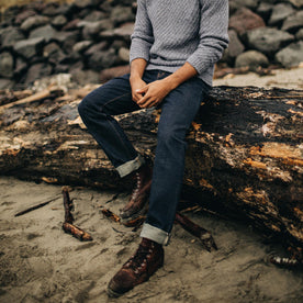 fit model on a log wearing The Slim Jean in Rinsed Organic Selvage
