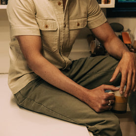 fit model sitting on the kitchen counter in The Democratic All Day Pant in Arid Eucalyptus Canvas
