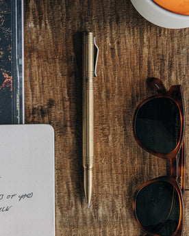material shot of The Pen in Brass on a wooden table, Accessories by Taylor Stitch
