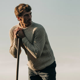 fit model wearing The Adirondack Sweater in Natural, leaning against oar