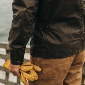 fit model wearing The Longshore Jacket in Dark Oak Waxed Canvas, holding gloves