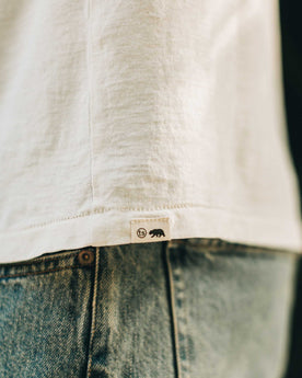 our fit model wearing The Standard Issue Tee in Natural Hemp—logo detail shot, Knits by Taylor Stitch
