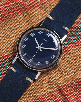 flatlay of the 1976 Timex Mercury Blue, on a striped background, Accessories by Taylor Stitch