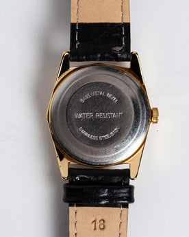 flatlay of the 1978 Timex Gold Marlin, shown from the back, Accessories by Taylor Stitch