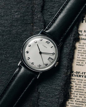 flatlay of the 1978 Timex Mercury, shown on a newspaper, Accessories by Taylor Stitch