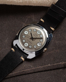 flatlay of 1975 Timex Electric Dynabeat "Rotary" against against a brown background, Accessories by Taylor Stitch