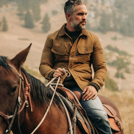 fit model wearing The Lined Long Haul Jacket in Harvest Tan Dry Wax, on horse, looking right