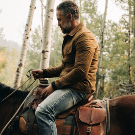 fit model wearing The Lined Long Haul Jacket in Harvest Tan Dry Wax, holding reins