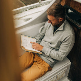 fit model reading on a boat in The Horizon Pullover in Ash Double Knit