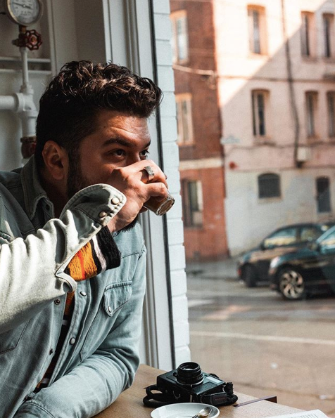 Andrew Calisterio, bartender, drinking a drink and looking outside