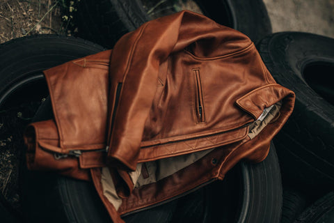 The Moto Jacket in Whiskey Steerhide on a pile of tires