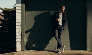 fit model leaning against the wall wearing The Stevens Suit in Navy Linen Seersucker