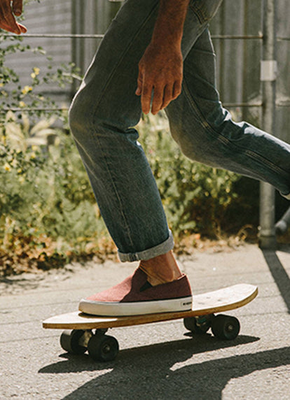 Man skating while wearing our maroon SeaVeesxTS slip on sneakers