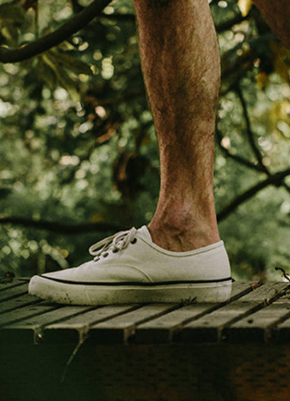 Man wearing our white slip ons on a dock