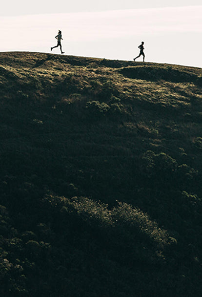 Two runners speeding down a hill of the Marin Headlands