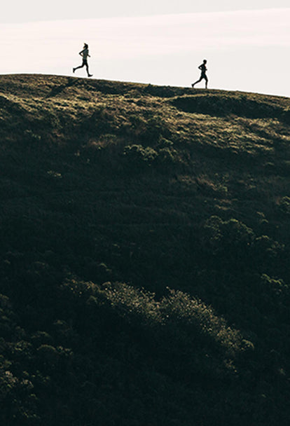 Two runners speeding down a hill of the Marin Headlands