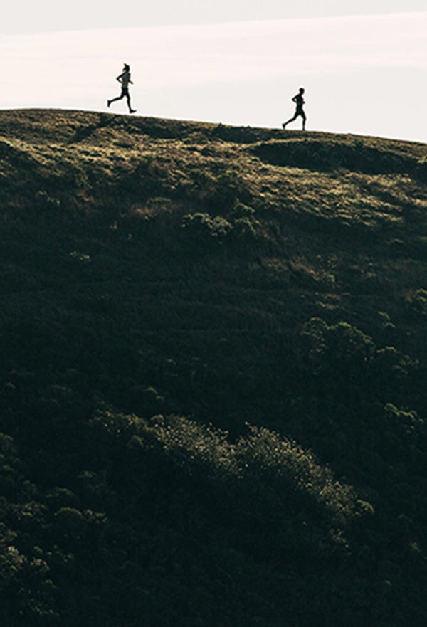 Two runners speeding down a hill of the Marin Headlands
