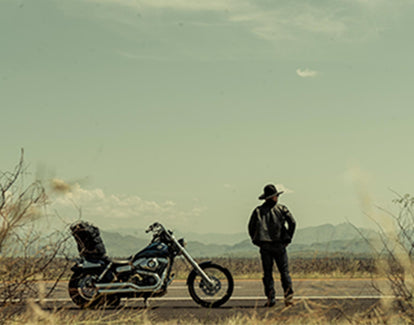 Man standing in front of his motorcycle on the Open Road