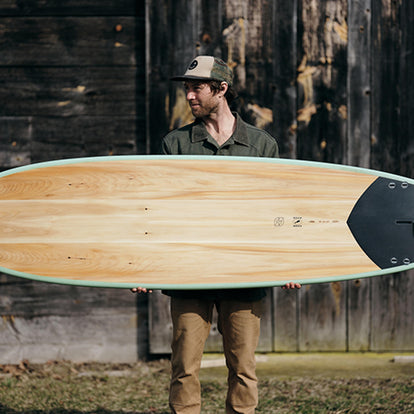 Man holding Grain Surfboard with TS Boss Duck inlays