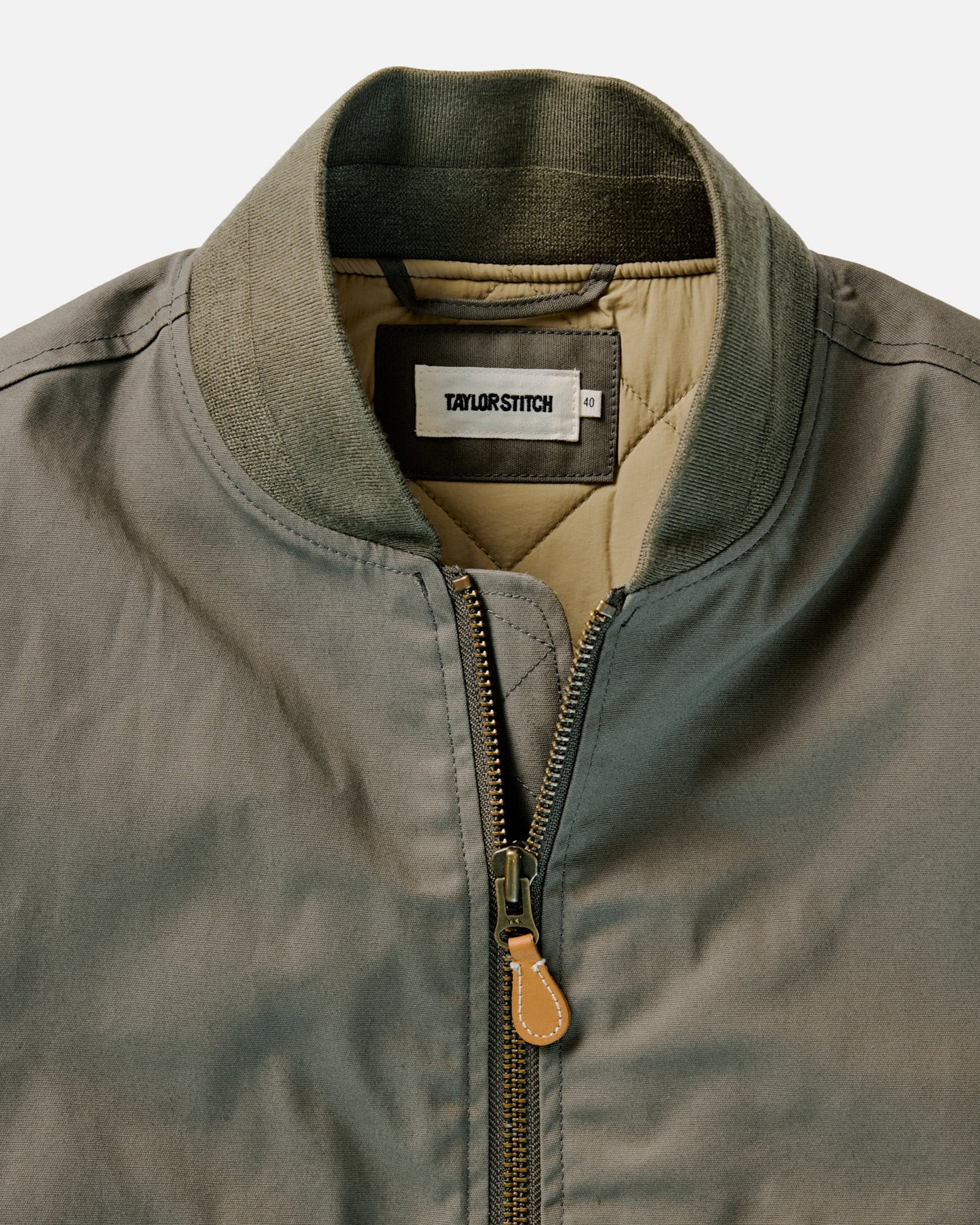 fit model leaning against a wall in The Insulated Bomber Jacket in Fatigue Olive Dry Wax, Outerwear by Taylor Stitch