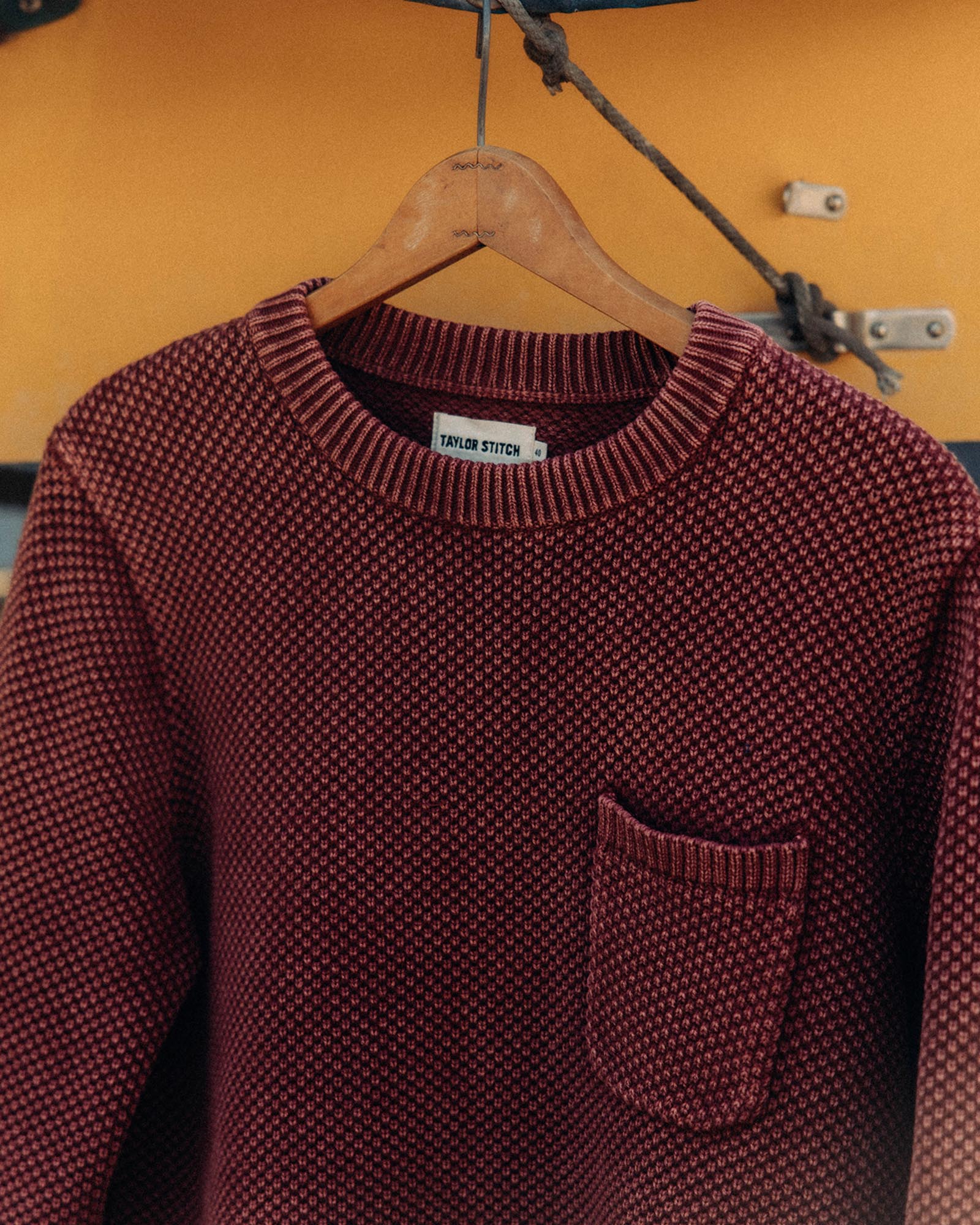 editorial image of The Crawford Crew Sweater in Dried Cherry hanging, Knits by Taylor Stitch