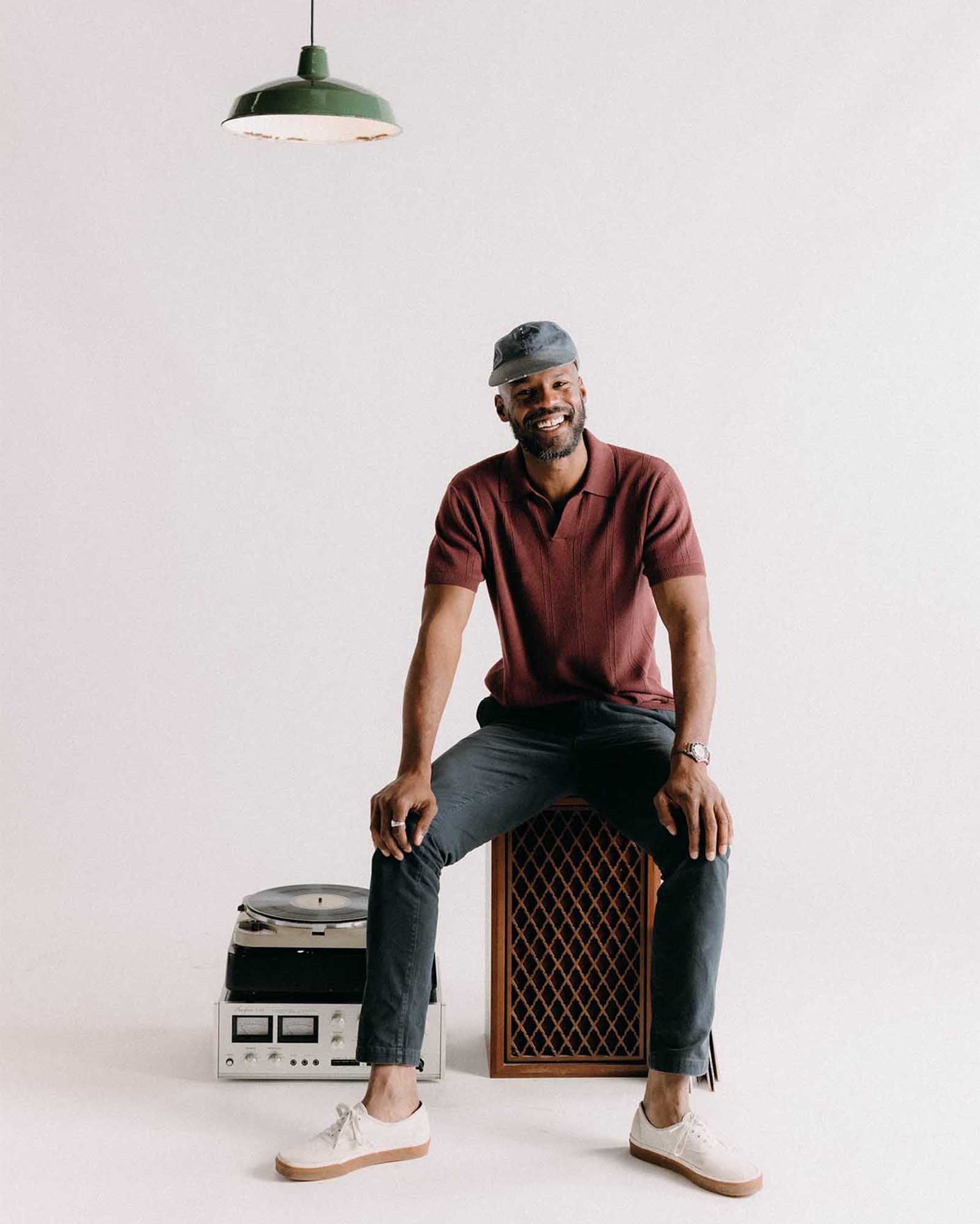fit model sitting on a speaker wearing The Slim Foundation Pant in Organic Navy, Bottoms by Taylor Stitch