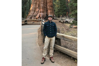 A man posing in front of a large sequoia.