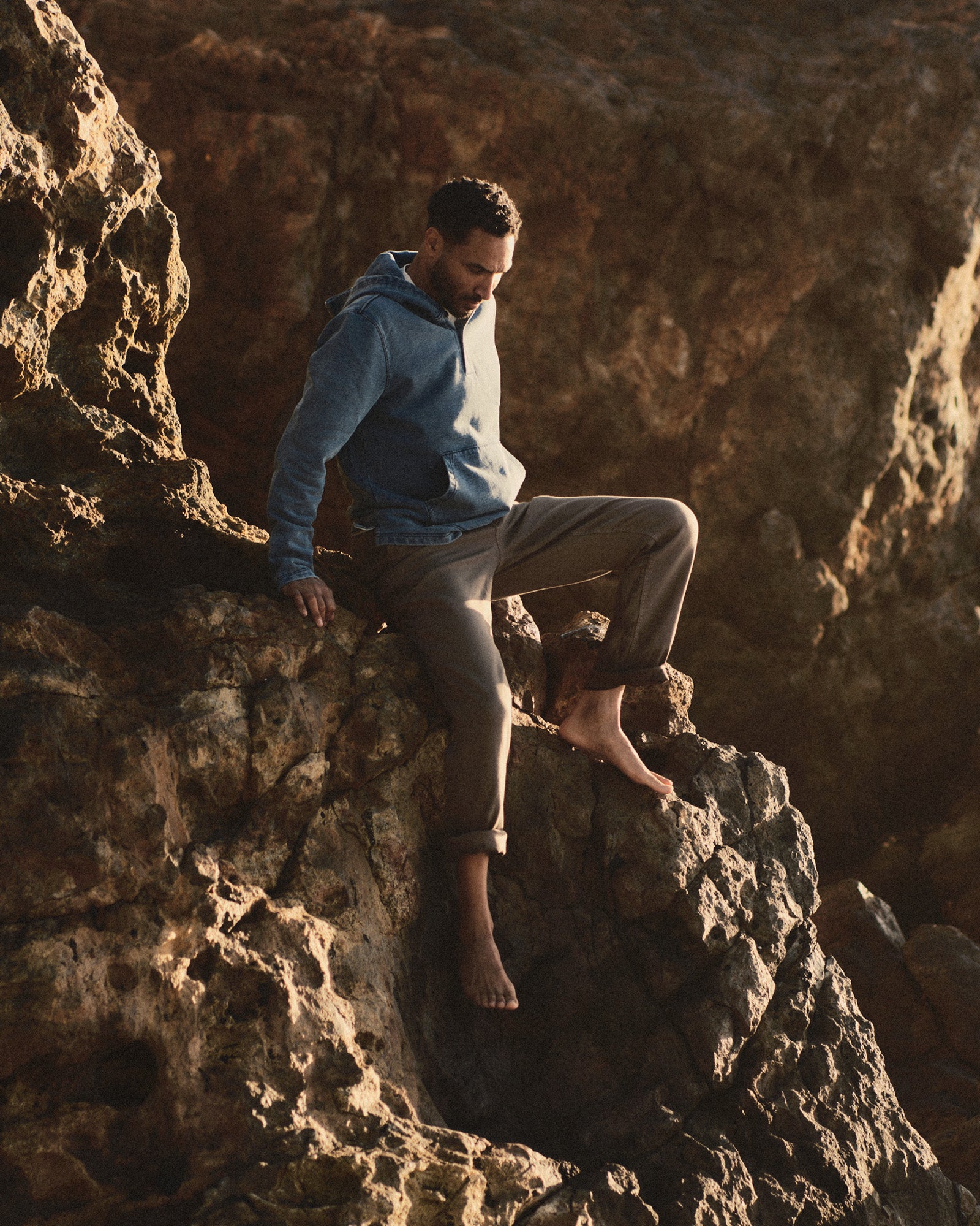 fit model sitting on rocks wearing The Baja Pullover in Washed Indigo Terry, Knits by Taylor Stitch