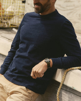 fit model leaning agains the wall wearing The Long Sleeve Shop Tee in Navy Twist